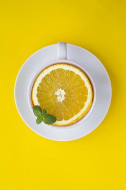Sarı arka planda taze portakallı beyaz çay bardağı. Üst Manzara. Uzayı kopyala Yaratıcı gıda kolajı. Konum dikey.