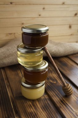 Kırsal ahşap arka planda küçük cam kavanozlardaki farklı bal çeşitleri. Konum dikey. Yakın çekim..
