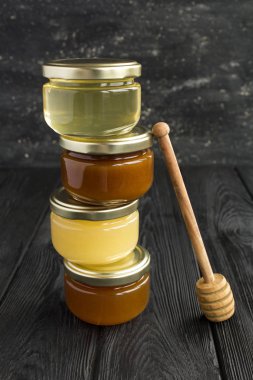 Siyah arka planda küçük cam kavanozlardaki farklı bal çeşitleri. Konum dikey. Yakın çekim..