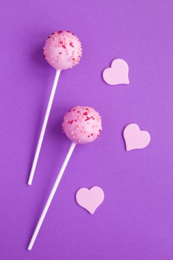 Pembe jöleli ve menekşe arka planında pembe kalpler olan kek çubukları. Üst Manzara. Uzayı kopyala Konum dikey.