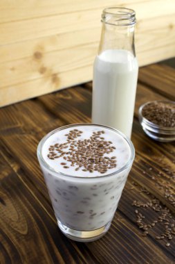 Yoğurt ya da kefir. Kahverengi ahşap arka plandaki bardakta keten tohumu var. Konum dikey.