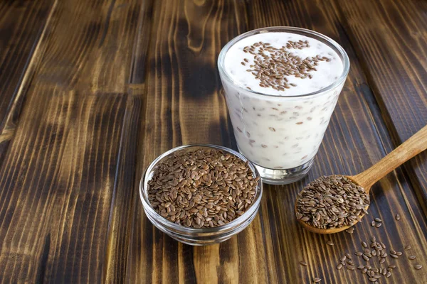 Yoğurt ya da kefir. Kahverengi ahşap arka plandaki bardakta keten tohumu var. Boşluğu kopyala.