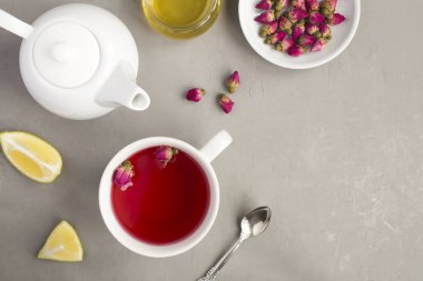 Gri beton arka planda beyaz fincanda pembe güller olan bitkisel çay. Üst Manzara. Boşluğu kopyala.