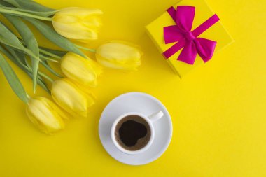 Sade kahve, pembe fiyonklu hediye ve sarı fonda sarı laleler. Üst Manzara. Boşluğu kopyala.