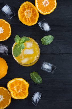 Siyah ahşap arka planda portakallı soğuk limonata. Konum dikey. Üst Manzara. Boşluğu kopyala.