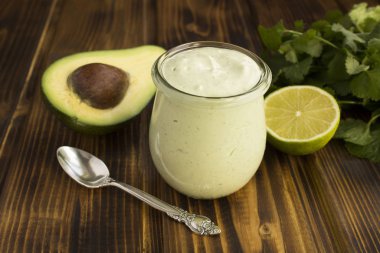 Yoğurtlu sos, avokado, kireç ve kahverengi ahşap arka planda kişniş. Yakın çekim..