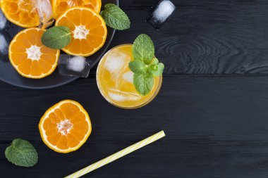 Siyah ahşap arka planda portakallı soğuk limonata. Üst Manzara. Boşluğu kopyala.
