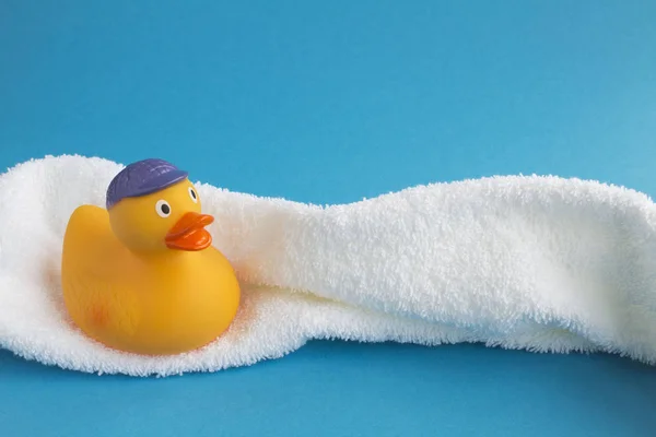 Banyo için sarı oyuncak ördek yavrusu ve mavi arka planda beyaz havlu. Uzayı kopyala Yakın çekim..