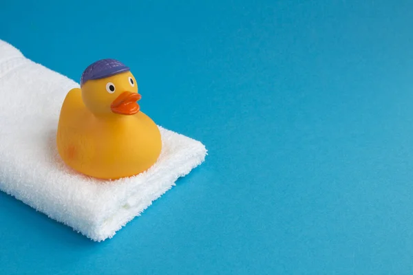Banyo için sarı oyuncak ördek yavrusu ve mavi arka planda beyaz havlu. Uzayı kopyala Yakın çekim..