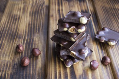 Kahverengi ahşap arka planda fındıklı koyu çikolata parçaları. Yakın çekim..