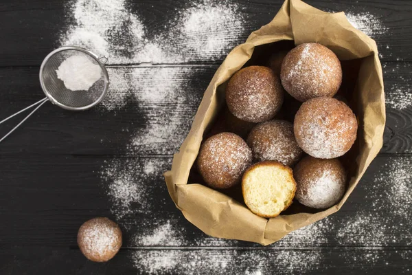 Siyah ahşap arka planda kağıt pakette ev yapımı süzme peynirli çörekler. Üst Manzara. Yakın çekim..