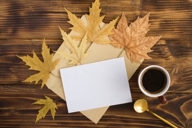 Seramik fincanda sade kahve, yazı için beyaz kağıt ve kahverengi ahşap arka planda kuru yapraklar. Üst Manzara. Uzayı kopyala Sonbahar bileşimi.