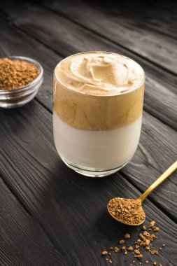 Siyah ahşap arka plandaki bardakta Dalgona kahvesi. Konum dikey.