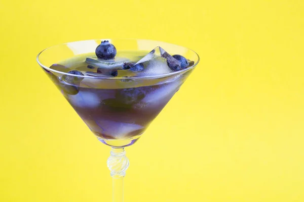Blauwe Cocktaildrank Met Ijs Bosbessen Een Martini Glas Gele Achtergrond — Stockfoto