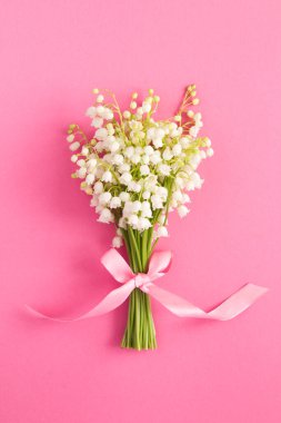 Pembe arka planda pembe kurdeleli vadi zambakları. Konum dikey. Üst Manzara. - Yakın çekim. Bahar çiçekleri kavramı.