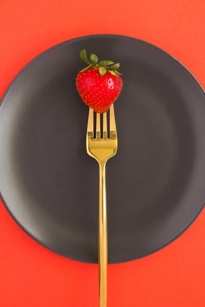 Una Fresa Empalada Tenedor Oro Plato Negro Sobre Fondo Rojo —  Fotos de Stock