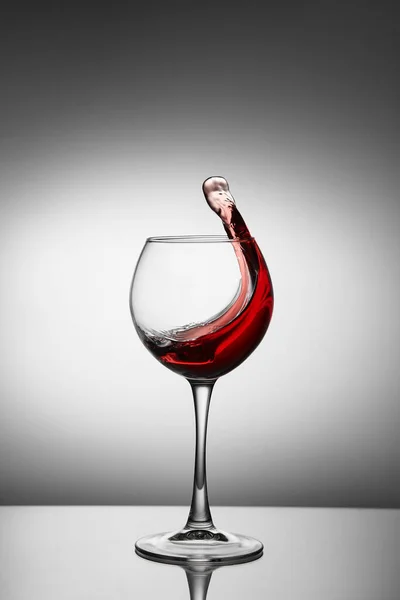 Glass with a splash of red wine on white background. Splashing red wine in a glass