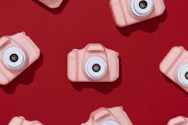 Kırmızı arka planda pembe oyuncak kamera deseni, üst manzara, yaratıcı kompozisyon. Geleceğin fotoğrafçısı, çocuk fotoğrafçısı.