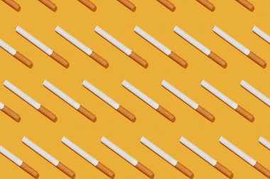 Sarı arka planda çapraz sigara deseni, üst görünüm, sigaranın yaratıcı kompozisyonu