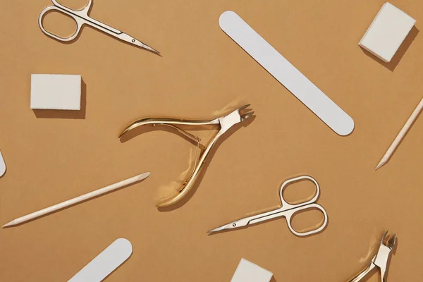 Pattern of cosmetic accessories for nails, scissors, pusher cuticle, cotton and dried flowers. Top view of manicure tools isolated on brown. manicure at home concept. top view.