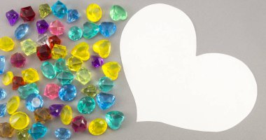 Gri arka planda beyaz kağıt kalp ve mücevherler