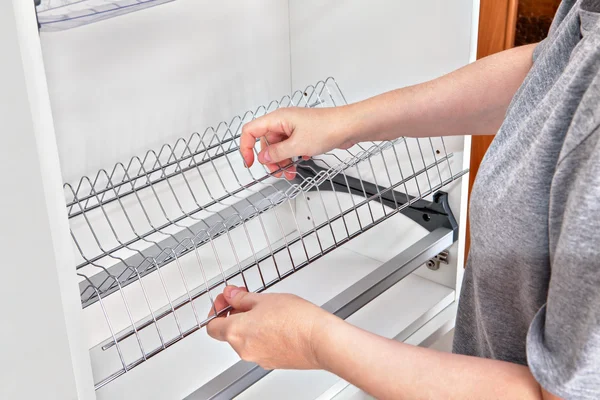 Instalação de prateleira de arame para secar pratos dentro do armário da cozinha . — Fotografia de Stock