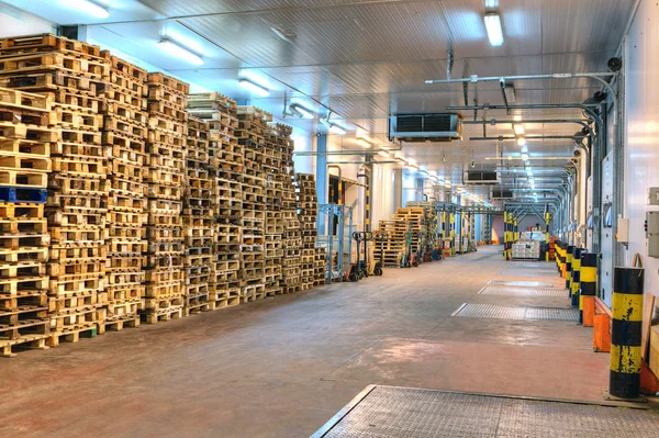 Equipo de muelle de carga, muchas paletas vacías apiladas dentro del almacén de almacenamiento . — Foto de Stock