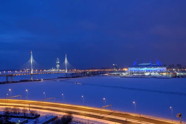 Night backlighting stayed bridge and football stadium in winter.