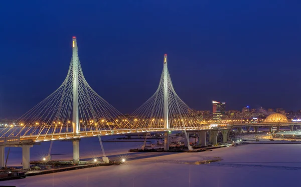 Шоссе пересекает замерзшую реку, оставаясь мостом ночью освещенный — стоковое фото