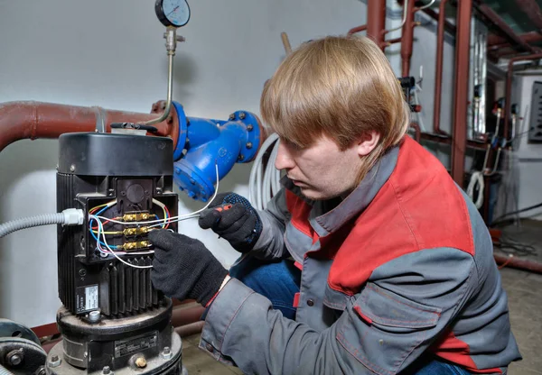 Système de chauffage de la pompe de réparation, le mécanicien relie les fils au moteur électrique . — Photo