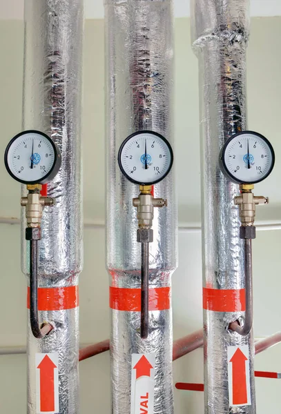 Manómetros en sala de calderas cerca de tuberías de calefacción con revestimiento aislante —  Fotos de Stock