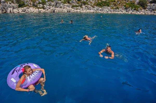 A small group of tourists bathes in the blue sea water. — Stock Photo, Image