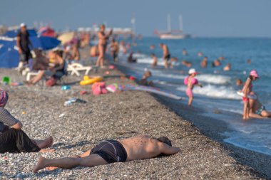 Tatilciler denizde yıkanmak ve çakıl sahilde güneşlenmek.