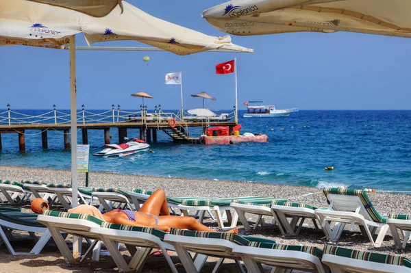 Abbronzatura ragazza, sdraiata sul lettino su una spiaggia deserta . — Foto Stock