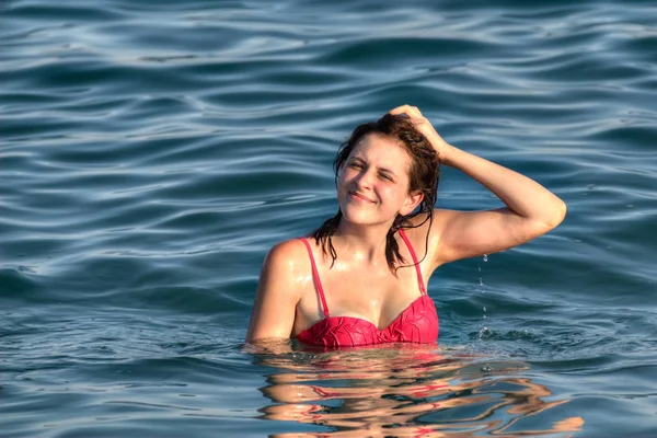 Caucasian teen girl in red swimsuit stands deep into sea. — Stock Image Caucasian teen girl in red swimsuit stands deep into sea. Stock Picture
