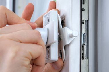 Close-up hands of locksmith  installing window limiter on plasti clipart