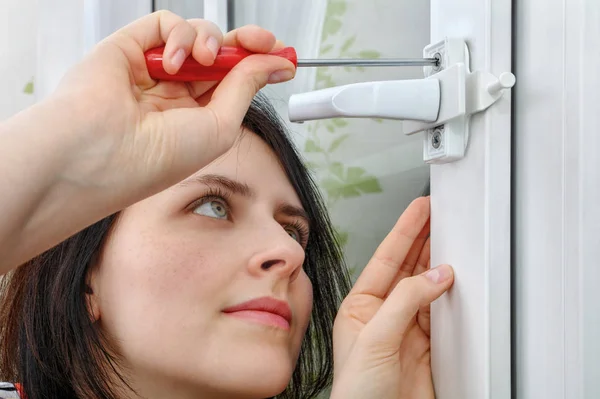 Dziewczyna instaluje ogranicznik okna ramki, ona zaciska skrew — Zdjęcie stockowe