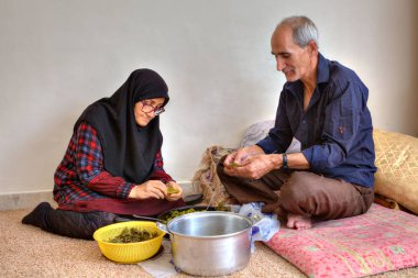 Elderly woman in hijab and her husband, cook at home. clipart