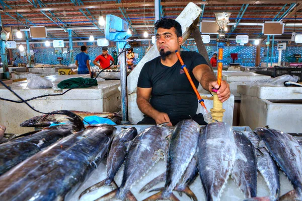 Färsk tonfisk lögner på is, fisk merchant röker vattenpipa. — Stockfoto
