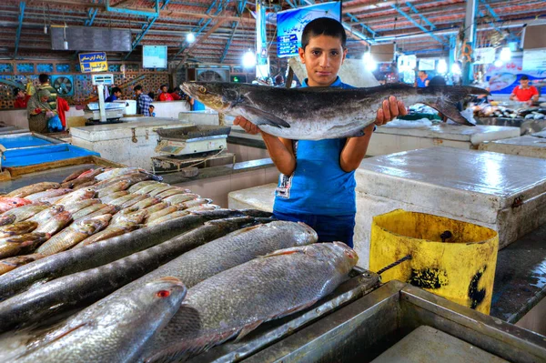 Chłopiec Perski przedsiębiorca pokazuje świeże ryby na rynku kryty. — Zdjęcie stockowe
