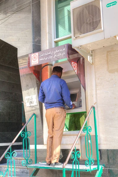 An Iranian man gets cash in an external ATM. — Stock Photo, Image