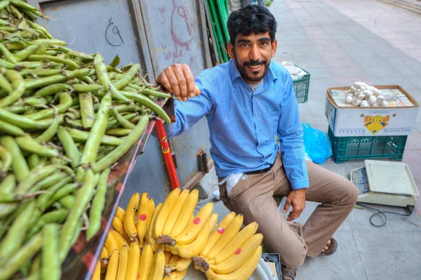 Vegetable trader smiles sitting next to his merchandise, souther — Stock Photo, Image