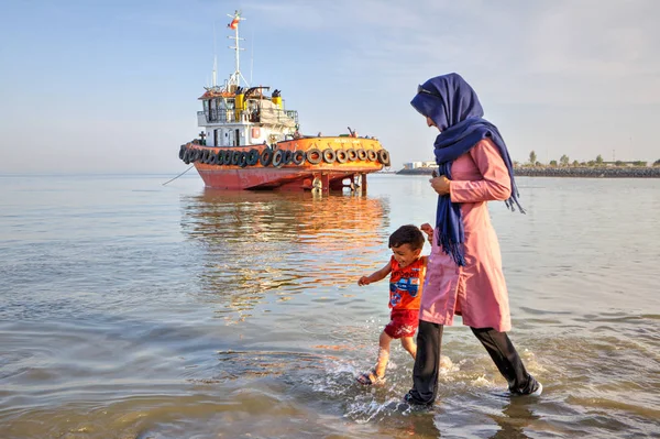 Junge Mutter spaziert mit ihrem Sohn am Ufer des Persischen Golfs. — Stockfoto