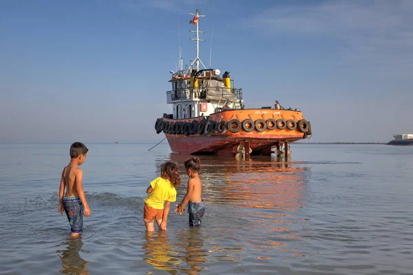 Three children bathing near the  stranded boat,  Hormozgan Provi — Stock Photo, Image