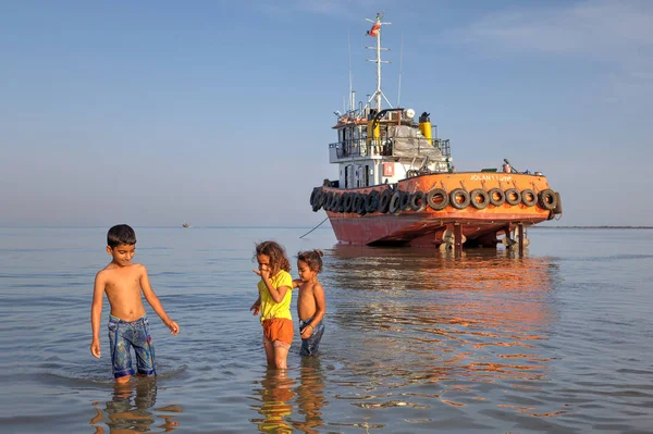 Los niños caminan sobre el agua cerca de la orilla del Golfo Pérsico, Irán . — Foto de Stock