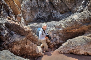 Kayalar, kamera ile arasındaki yolda bir gülümseyen backpacker gider