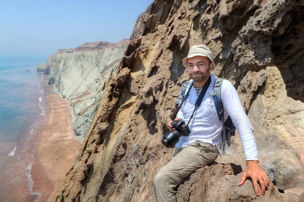 Feliz fotógrafo viajero sentado en el borde de un acantilado . —  Fotos de Stock