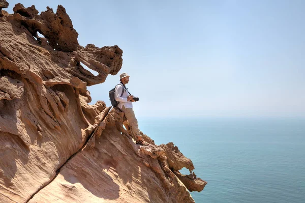 Fotógrafo de la naturaleza de pie en el borde del acantilado sobre el mar . —  Fotos de Stock