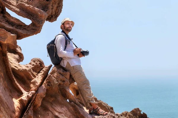 Reisender mit Kamera sitzt am Rande einer Klippe. — Stockfoto