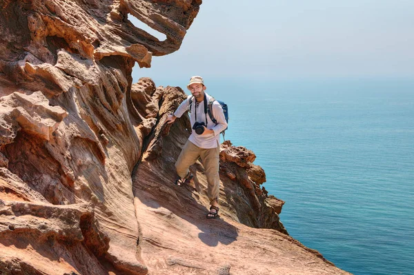 Cliff deniz, Hürmüz Adası üzerinde turist fotoğrafçı tırmanıyor, 